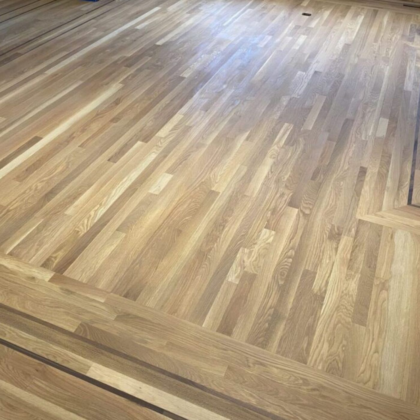 Mid-century hardwood floor restoration with 2.25 inch solid white oak planks and walnut border inlays finished with WOCA Diamond Oil Active Sand Gray by LUKS Construction Seattle Bellevue